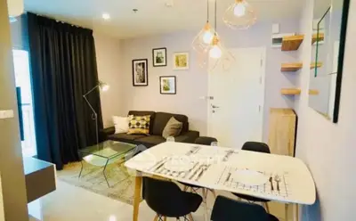 Stylish modern living room with dining area, featuring chic lighting and cozy decor.