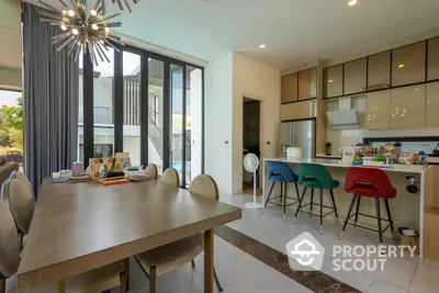 Spacious modern kitchen with open layout, sleek cabinetry, and vibrant bar stools, complemented by a large dining area and stylish lighting.