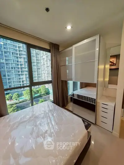 Modern bedroom with large window and city view, featuring sleek furniture and natural light.