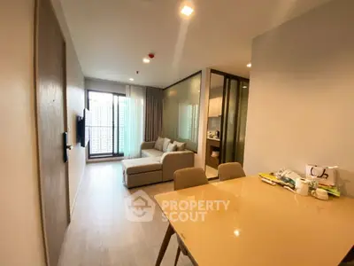 Modern living room with open kitchen and balcony view in stylish apartment.