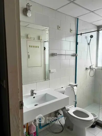 Modern bathroom with white tiles, sleek sink, and shower area, perfect for a contemporary home.