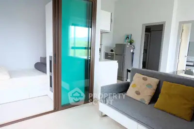 Modern apartment interior with cozy living room and glass partitioned bedroom