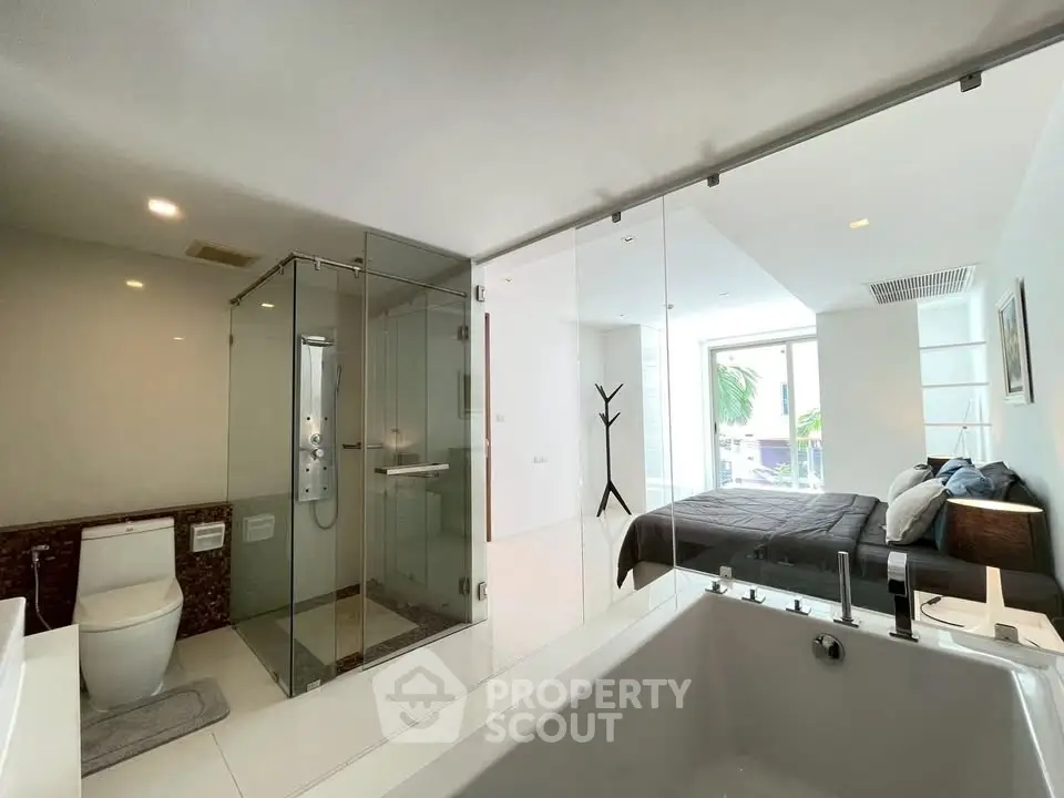Luxurious open-plan bedroom with modern ensuite bathroom featuring glass shower and bathtub.
