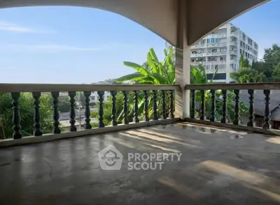 Spacious balcony with scenic view of lush greenery and modern building, perfect for relaxation.