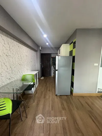 Modern kitchen with sleek design, featuring a stainless steel fridge and stylish green chairs.
