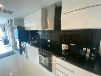 Modern kitchen with sleek black countertops and built-in appliances in open layout.