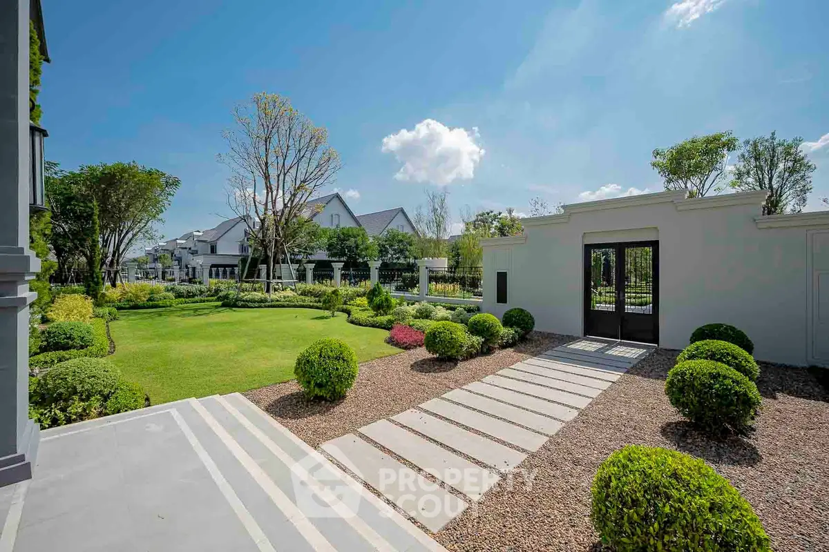 Luxurious garden view with manicured lawn and elegant pathway in upscale residential area.