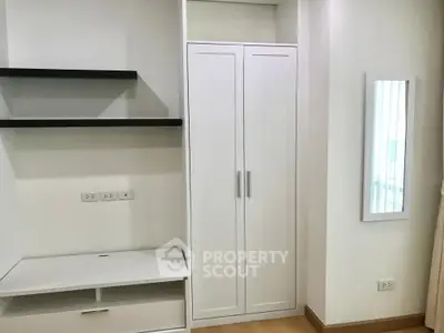 Modern minimalist bedroom with sleek white wardrobe and built-in shelves