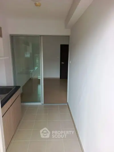 Modern kitchen with sleek design and sliding glass door leading to a spacious room.