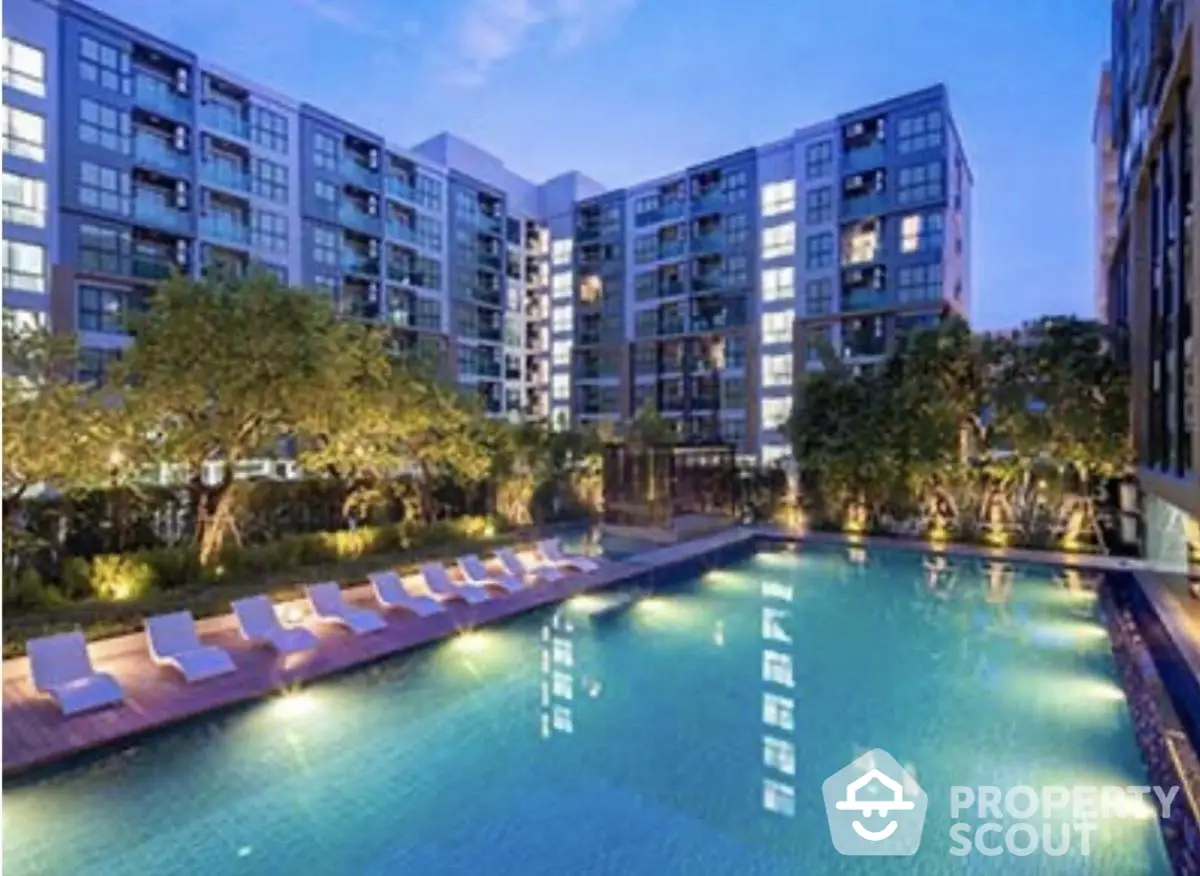 Luxurious condominium with illuminated pool and lush garden view at dusk.