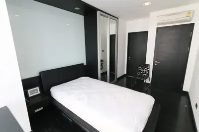Modern minimalist bedroom with sleek black and white decor and mirrored wardrobe.