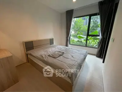 Modern bedroom with large window and garden view, featuring stylish decor and natural light.