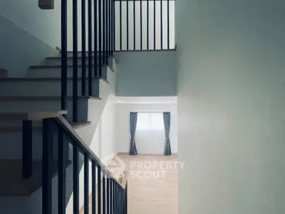 Modern staircase with wooden steps and sleek metal railing in a spacious home interior