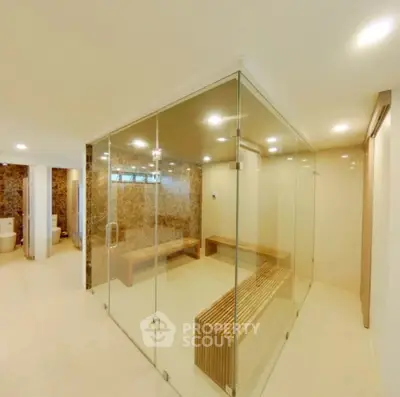Luxurious spa-like bathroom with glass-enclosed sauna and elegant design.