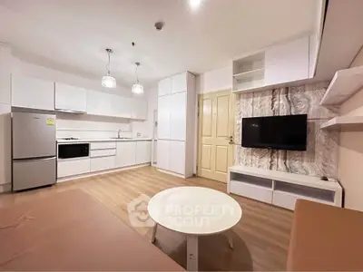 Modern open-plan living room with sleek kitchen, TV, and stylish decor in a contemporary apartment.