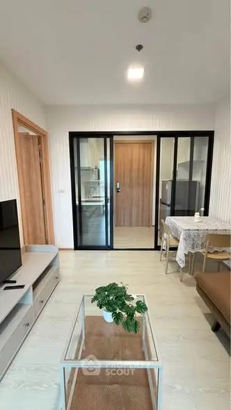 Modern living room with glass partition, cozy seating, and stylish decor in a contemporary apartment.