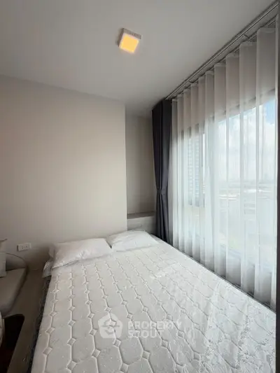 Modern bedroom with large window and natural light in a stylish apartment.