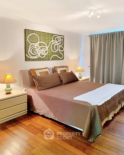 Spacious bedroom with elegant decor and hardwood floors, featuring a cozy bed and ambient lighting.