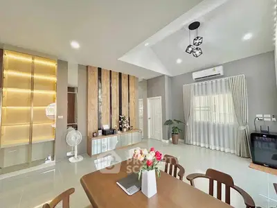 Modern living room with elegant decor and stylish lighting, featuring a dining table and built-in shelves.