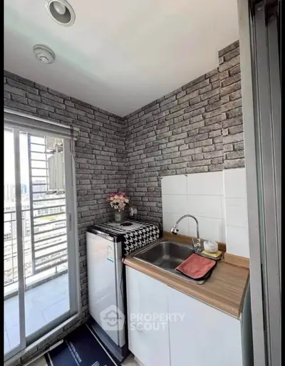 Charming compact kitchen with brick wall and balcony view, perfect for urban living.
