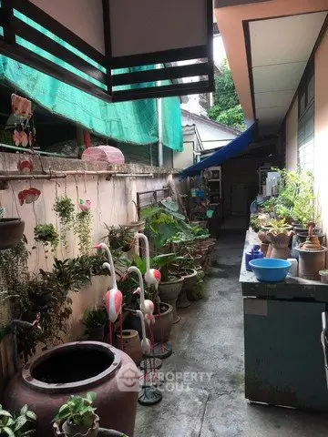 Charming outdoor corridor with lush potted plants and rustic decor, perfect for a serene garden retreat.