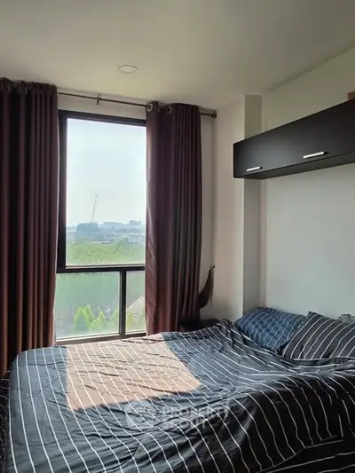 Cozy bedroom with large window offering a scenic view, perfect for relaxation and comfort.