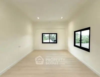 Spacious empty room with large windows and wooden flooring, perfect for customization.