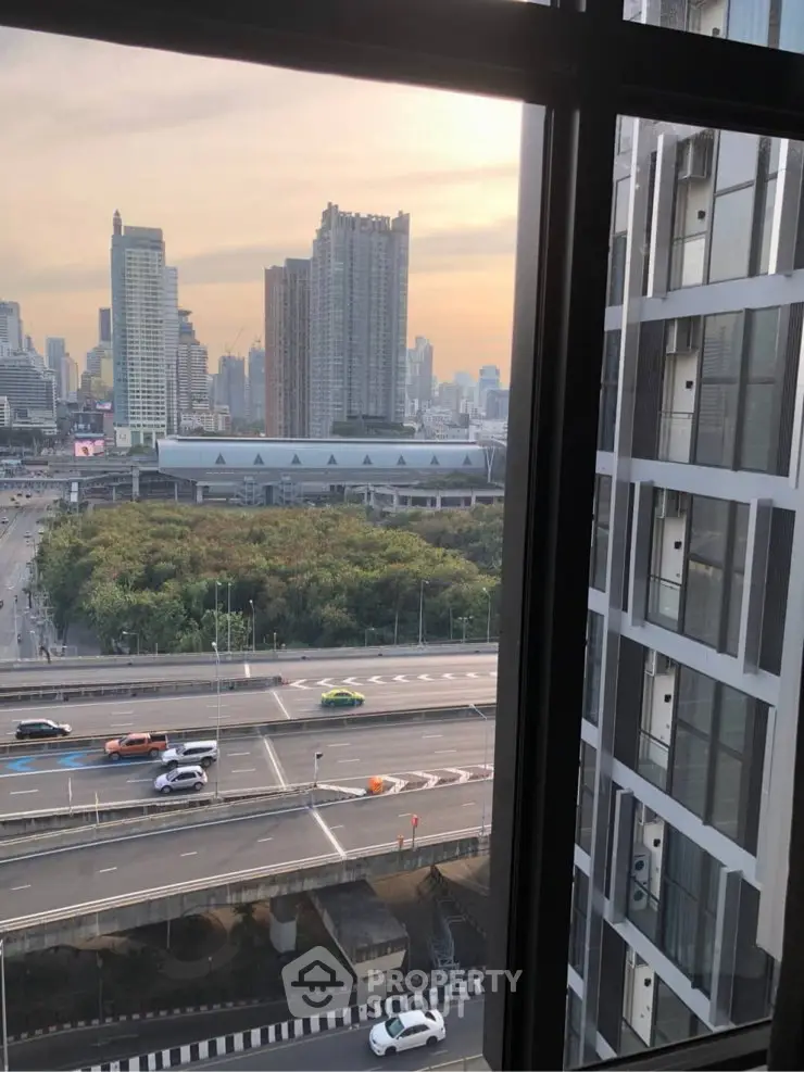 Stunning cityscape view from high-rise window overlooking urban skyline and lush greenery.