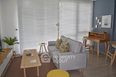 Modern living room with stylish furniture and large windows with blinds, perfect for relaxation and entertainment.