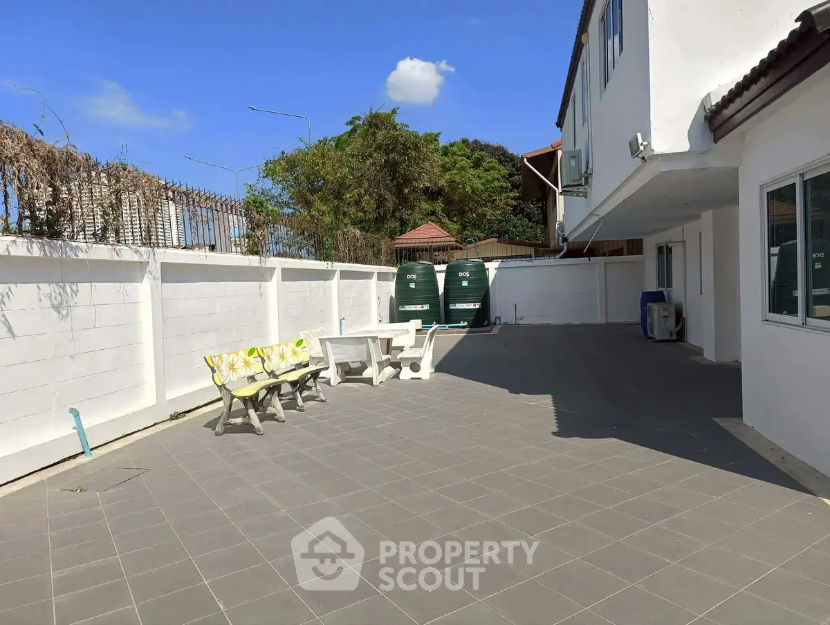 Spacious outdoor patio with seating and storage tanks in a sunny residential area.