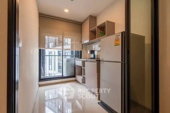 Modern kitchen with sleek design and large window offering natural light in a contemporary apartment.