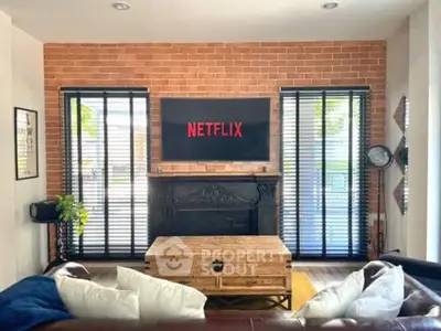 Charming living room with brick accent wall and modern decor, featuring a mounted TV and cozy seating area.