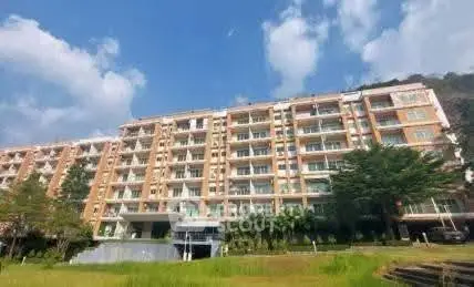 Stunning multi-story residential building with lush greenery and clear blue sky backdrop.