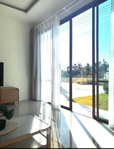 Bright living room with large sliding glass doors opening to a sunny garden view, featuring modern decor.
