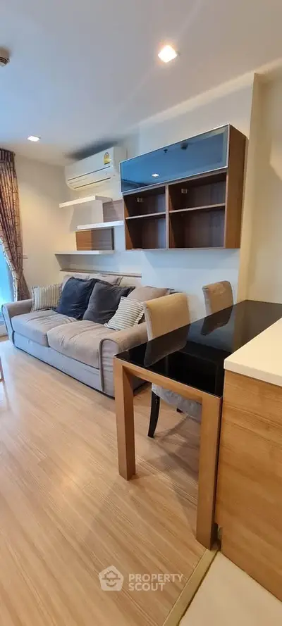 Modern living room with stylish furniture and wooden flooring, featuring a cozy sofa and elegant shelving.