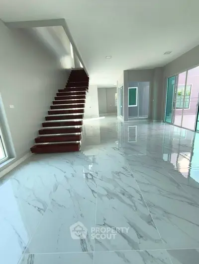 Spacious modern living room with glossy marble flooring and sleek staircase.