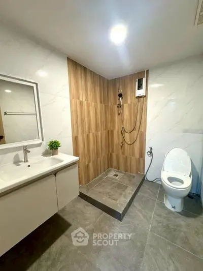 Modern bathroom with sleek design, featuring a shower area, toilet, and stylish vanity.