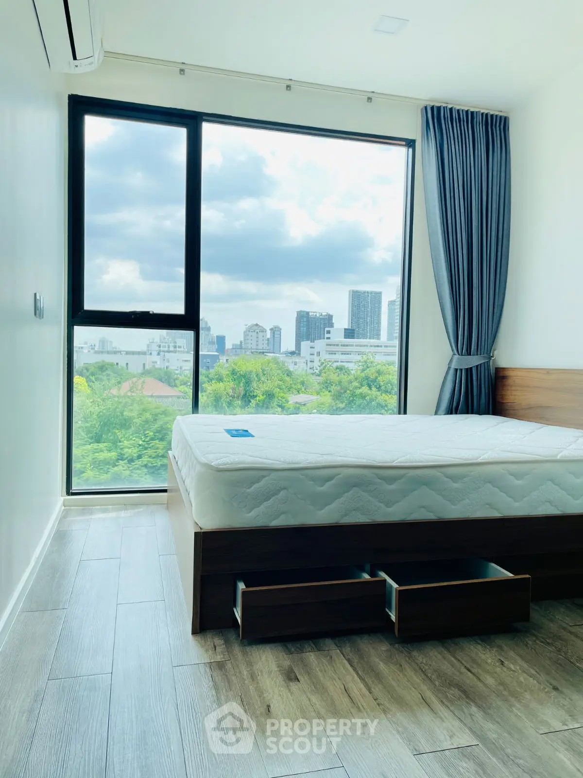 Modern bedroom with large window offering stunning city view and natural light