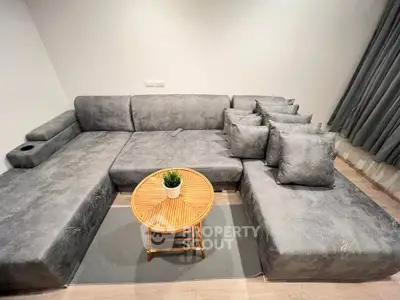 Modern living room with stylish gray sectional sofa and round wooden coffee table