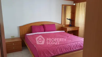 Cozy bedroom with wooden furniture and vibrant pink bedding, perfect for a restful retreat.