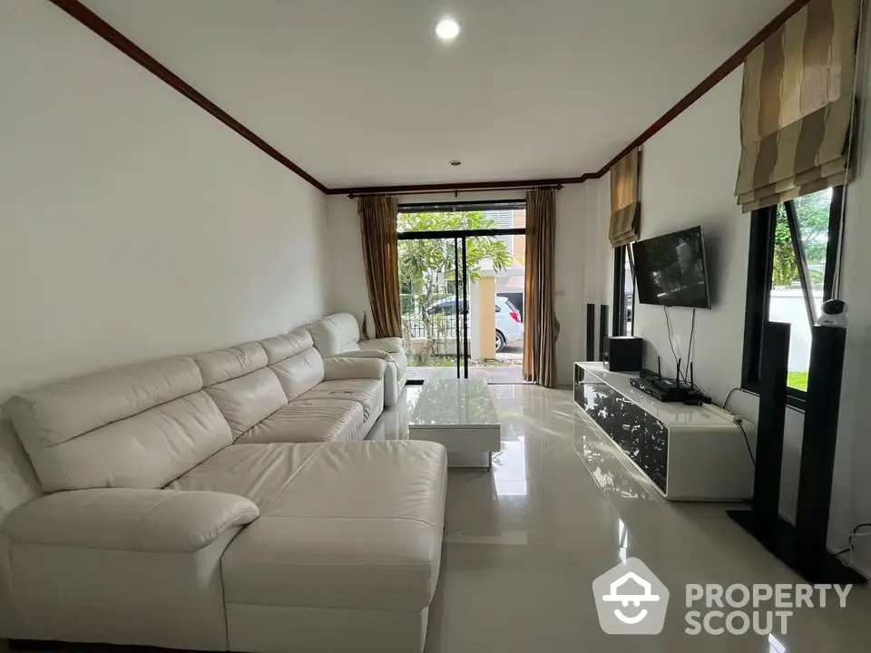 Spacious modern living room with white leather sectional sofa and large windows