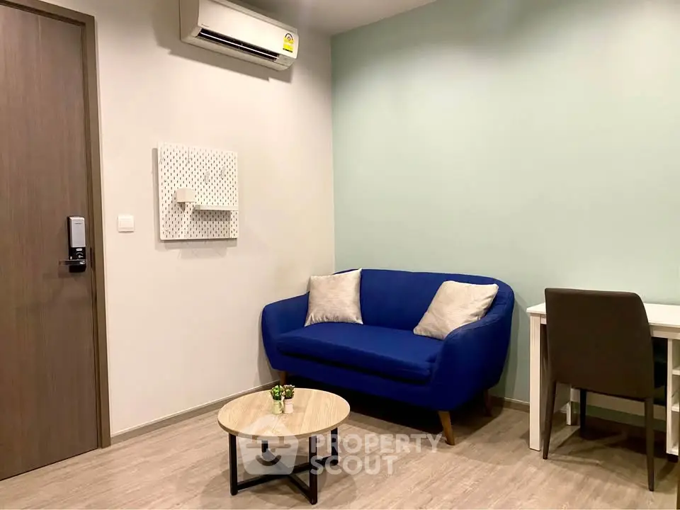 Modern living room with blue sofa, desk, and air conditioning in a cozy apartment.