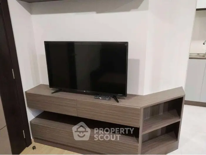 Modern living room with sleek TV stand and flat-screen TV, showcasing minimalist design and functionality.