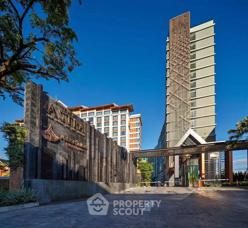 Modern high-rise building with unique architectural design and spacious entrance in urban setting.
