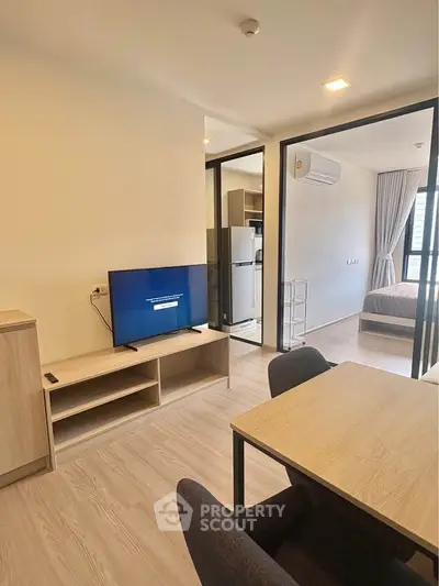 Modern apartment interior with open living area and kitchen, featuring sleek furniture and natural light.