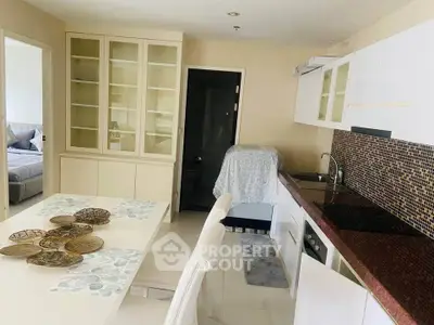 Modern kitchen with sleek cabinets and dining area in open layout apartment.