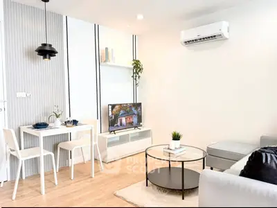 Modern living room with stylish decor, featuring a cozy seating area, wall-mounted TV, and dining space.