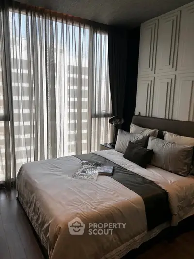 Luxurious bedroom with elegant decor and large windows offering natural light in a modern apartment.