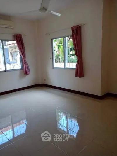 Spacious empty room with tiled floor and large windows, perfect for customization.
