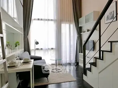 Modern loft-style living room with high ceilings and elegant staircase